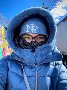 Ragazza vestita di azzurro, molto coperta per il freddo: si vedono solo gli occhi.